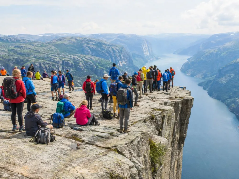 Senderistas sentados y de pie en el borde sin protección de la meseta de Preikestolen