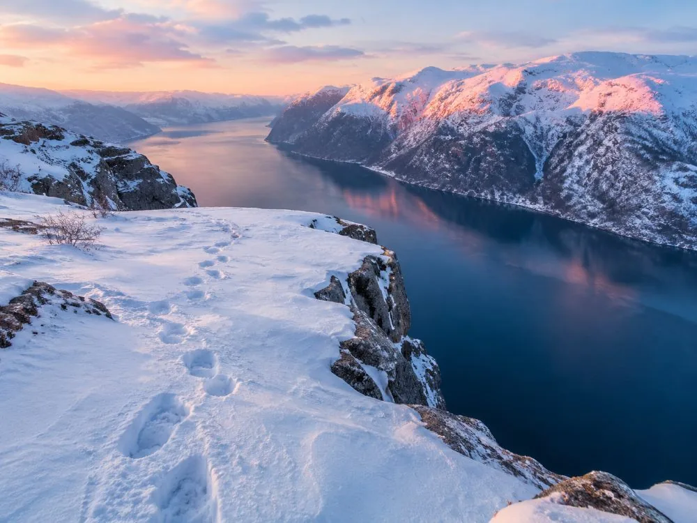 El sendero al Preikestolen bajo la nieve, con un grupo guiado equipado con ropa de invierno y crampones